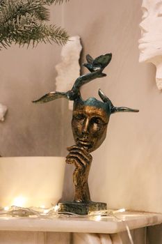 A bronze sculpture of an abstract face with details on a mantel, offering a modern artistic touch.