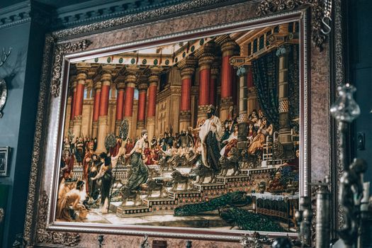 A framed historical painting depicting a classical scene in a gallery setting.
